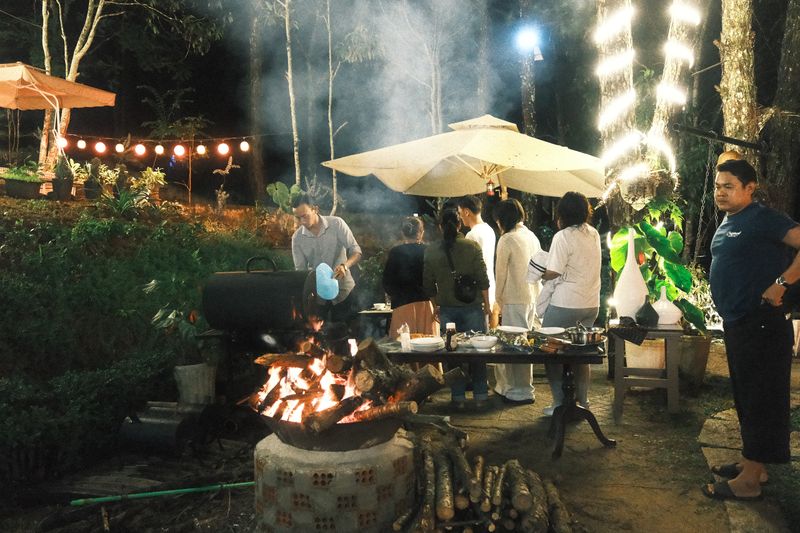 Nhóm bạn đứng quanh lửa trại và bếp nướng buổi tối tại GIA AN